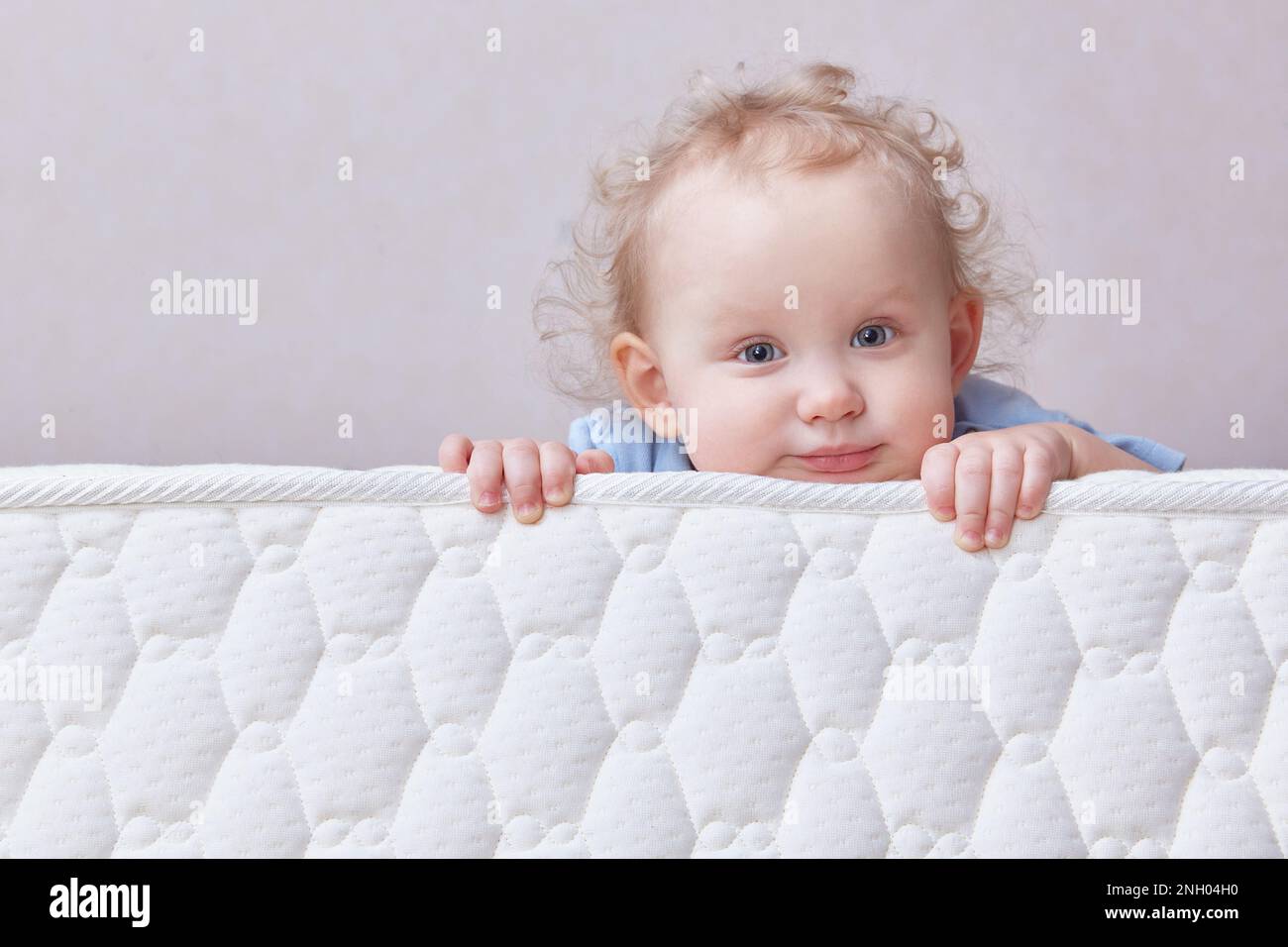 Cute thoughtful curly-haired todd is lying on the mattress. Copy space Stock Photo