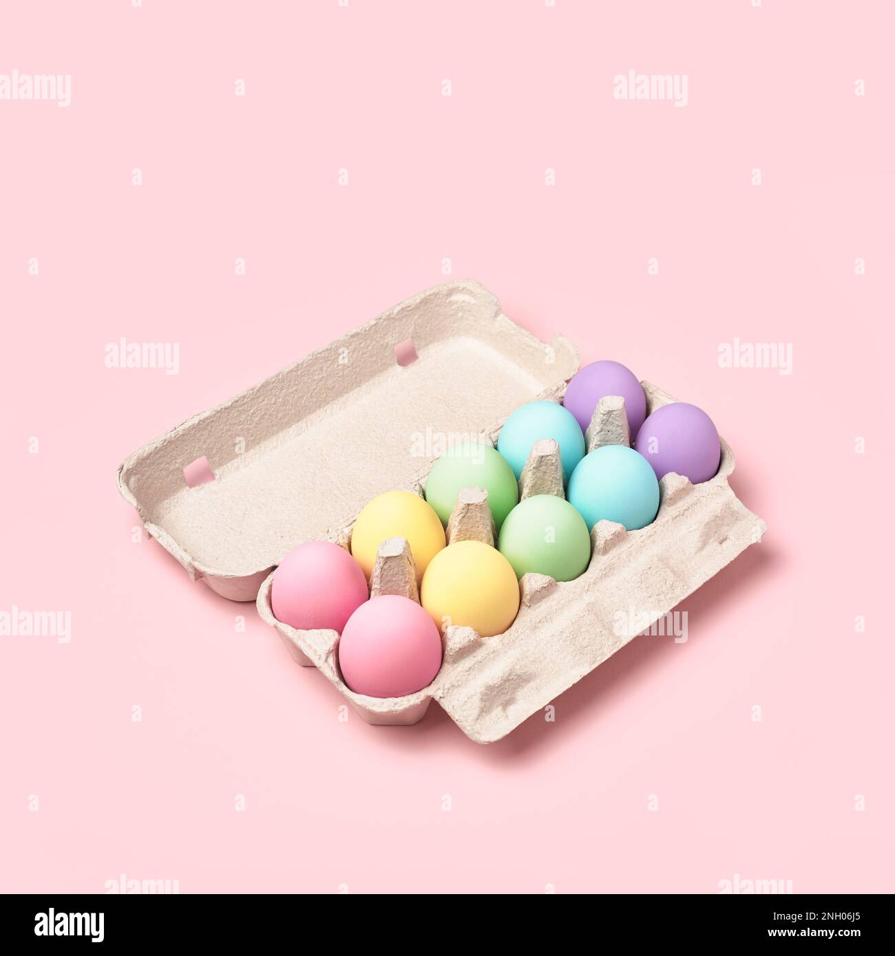 Pastel colored Easter Eggs in egg box on pink background. Rainbow, minimal style. Easter greeting card. Stock Photo