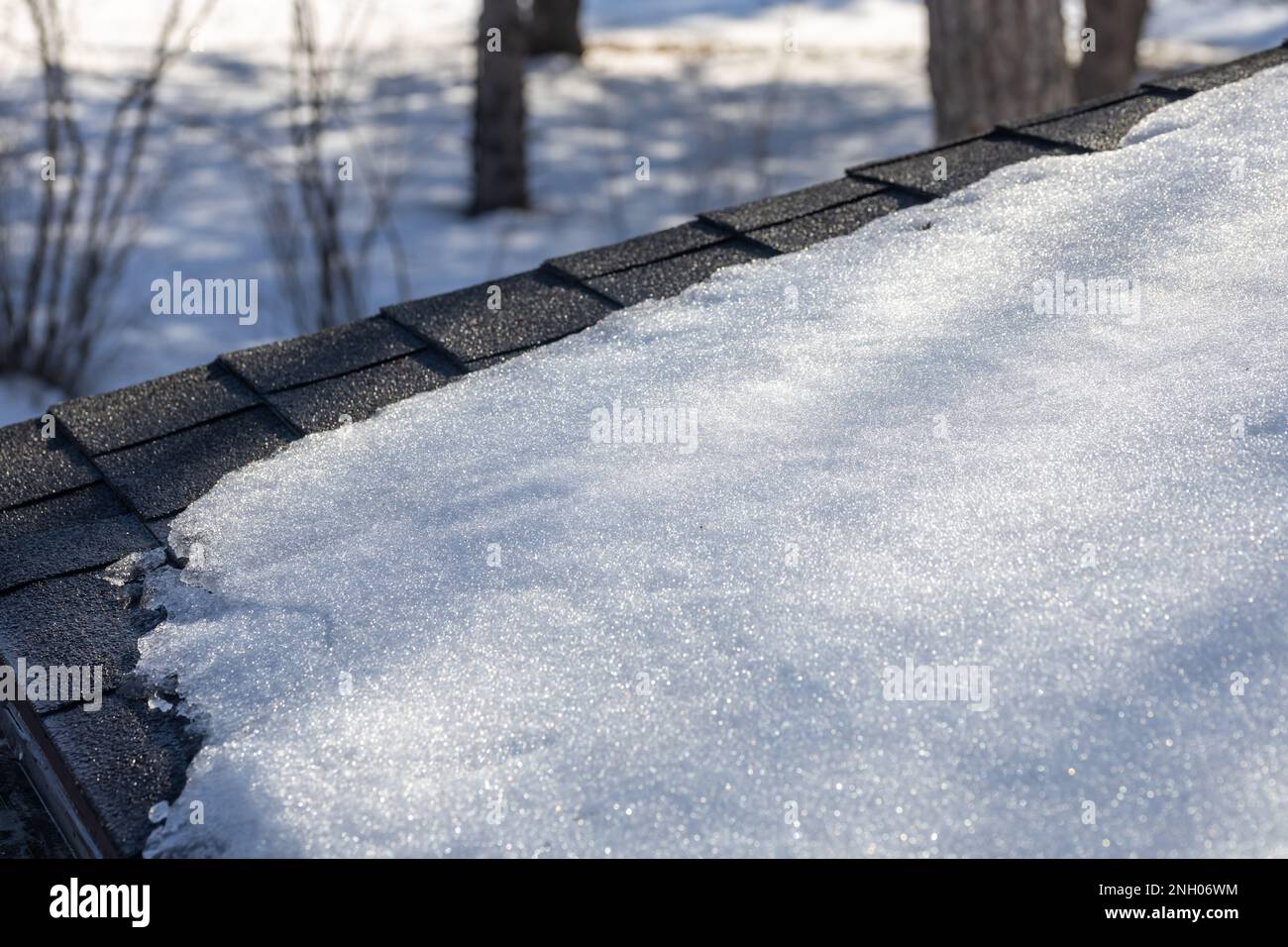 Full frame abstract texture background of snow beginning to melt on an asphalt shingle roof, under natural sunlight Stock Photo