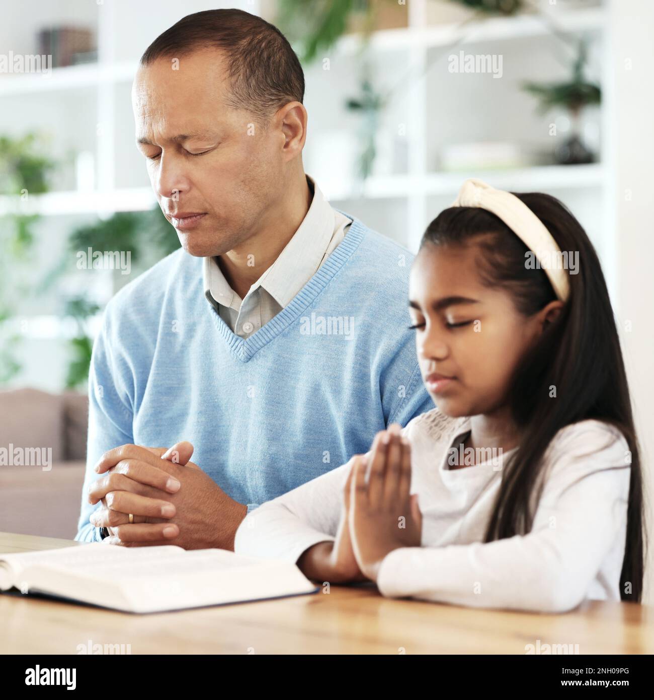 Bible books, family and child in prayer for support, faith and christian worship at home. Father, girl kid and praying of religion, spiritual trust or Stock Photo