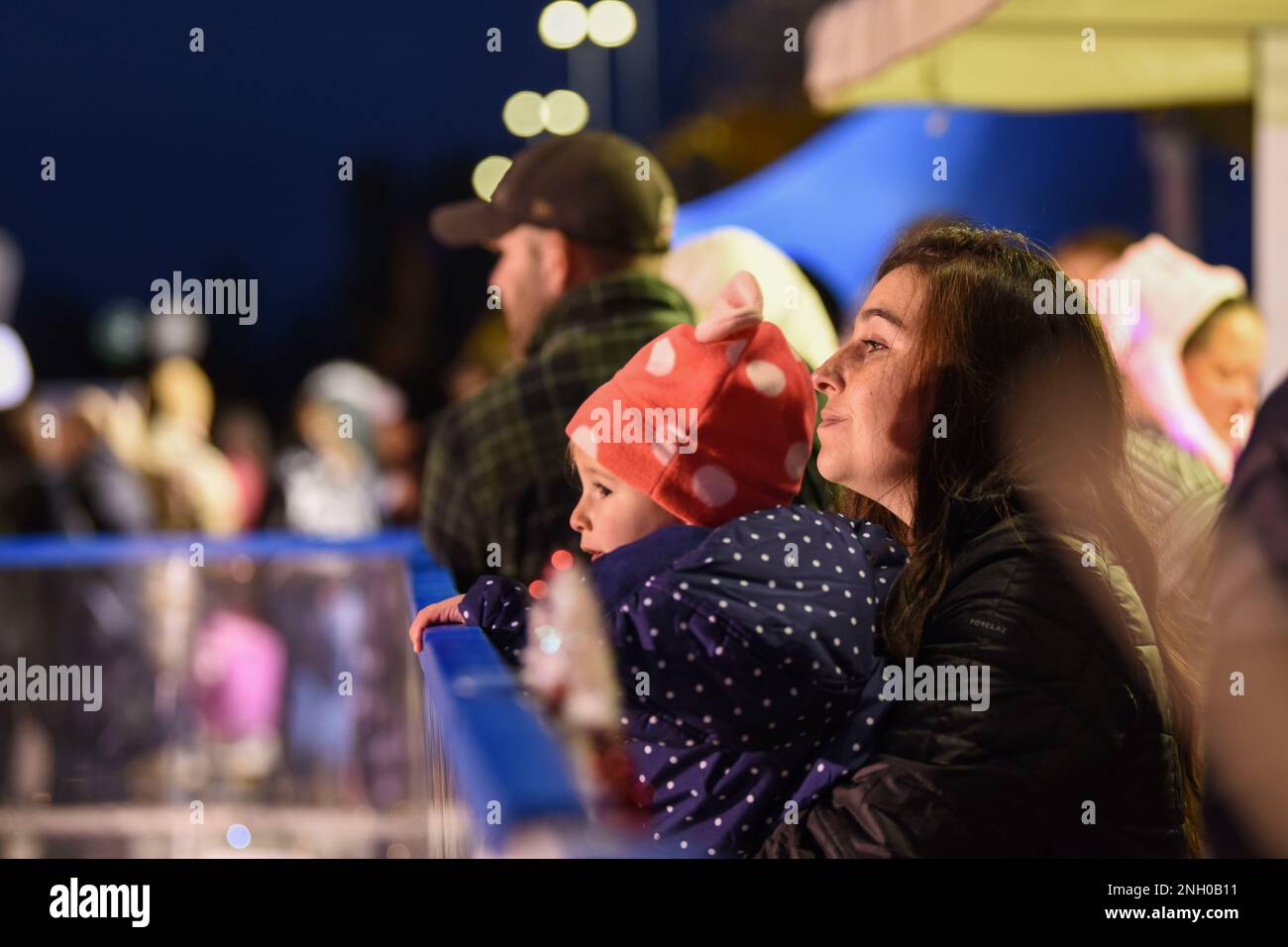 A mother and child watch ice-skaters during the annual Wyvern Wonderland event at Aviano Air Base, Italy, Dec. 2, 2022. During the event families enjoyed hot chocolate, ice-skating, and other festive attractions before ending the night with a tree lighting ceremony hosted by U.S. Air Force Brig. Gen. Tad Clark, 31st Fighter Wing commander and Italian Air Force Lt. Col. Riccardo Isoli, ‘Pagliano e Gori’ Airport operations chief. Stock Photo