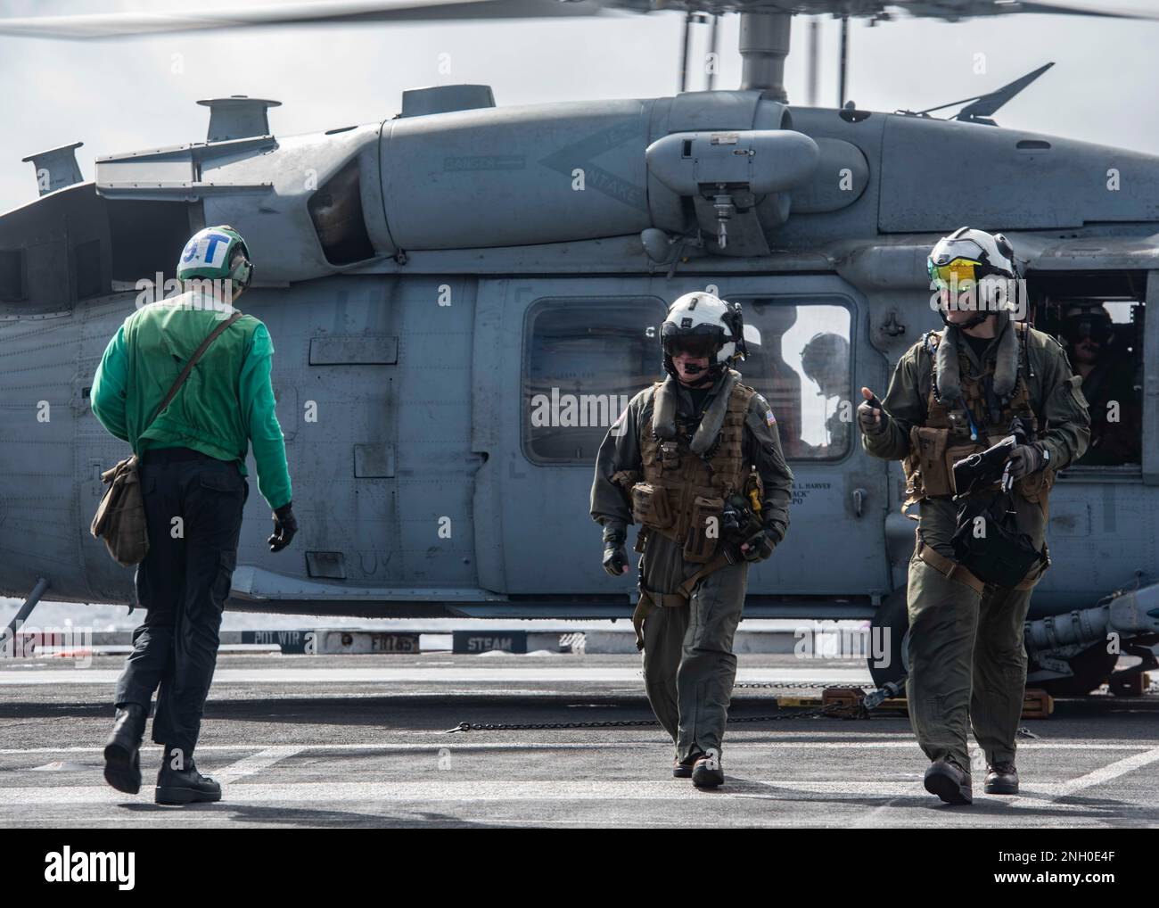 221204-N-UF592-2410 PHILIPPINE SEA (Dec. 4, 2022) Capt. Daryle Cardone, center, commanding officer of the U.S. Navy’s only forward-deployed aircraft carrier, USS Ronald Reagan (CVN 76), disembarks from an MH-60S Seahawk, attached to the Golden Falcons of Helicopter Sea Combat Squadron (HSC) 12, in the Philippine Sea, Dec. 4. HSC 12, originally established as Helicopter Anti-Submarine Squadron (HS) 2 on March 7, 1952, is the oldest active operational Navy helicopter squadron. Ronald Reagan, the flagship of Carrier Strike Group 5, provides a combat-ready force that protects and defends the Unite Stock Photo