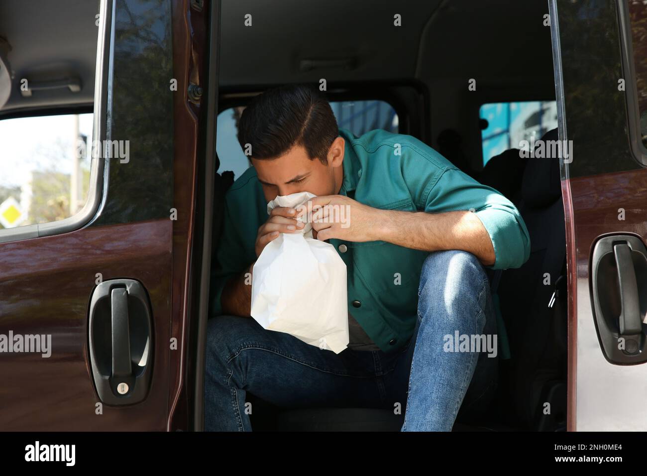 Man with paper bag suffering from nausea in car Stock Photo Alamy