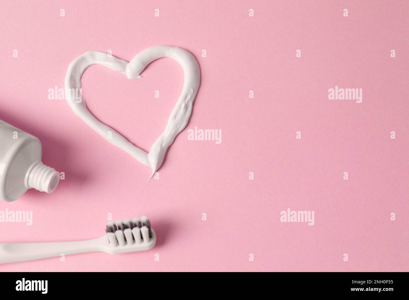 Heart made with toothpaste, tube and brush on pink background, flat lay. Space for text Stock Photo