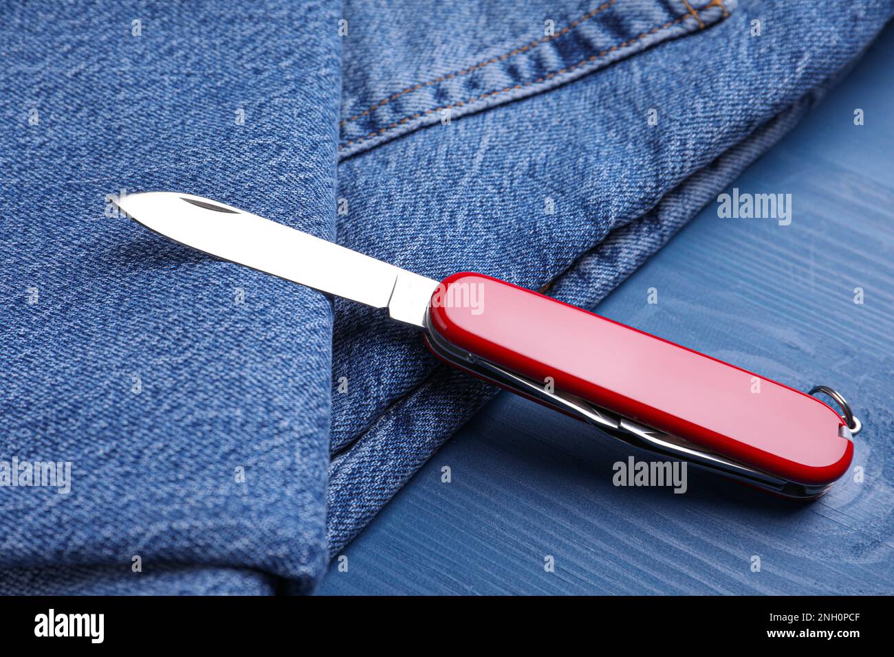 https://c8.alamy.com/comp/2NH0PCF/modern-compact-portable-multitool-and-jeans-on-blue-wooden-table-2NH0PCF.jpg