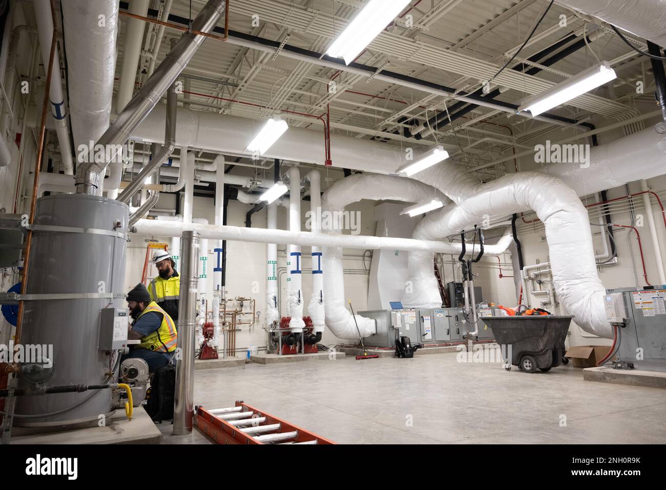 Programmers work in a mechanical room at the KC-46A Pegasus 3-bay maintenance hangar construction site at Travis Air Force Base, California, Dec. 5, 2022. The facility will be utilized for the maintenance and upkeep of Travis AFB’s future KC-46 tanker jet inventory upon the hangar’s completion in 2023. Stock Photo