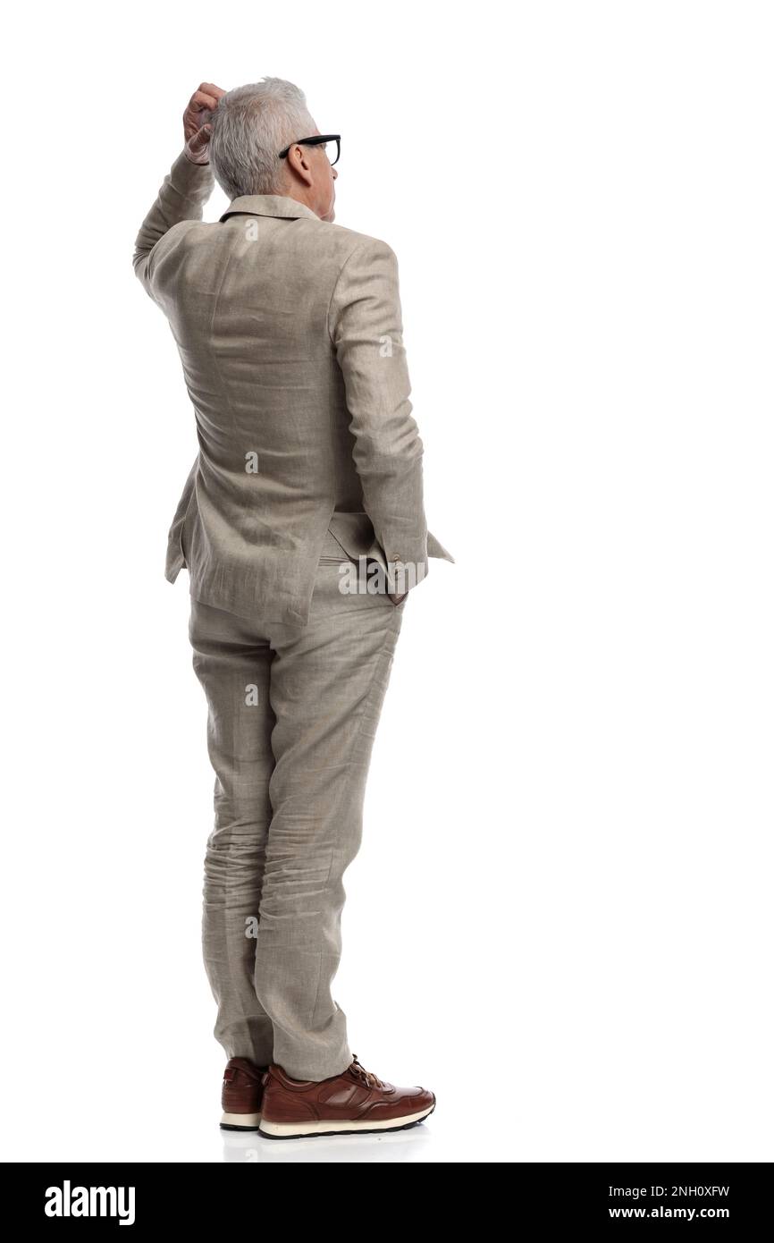 behind view of old man in his 60s scratching head and thinking, being ...
