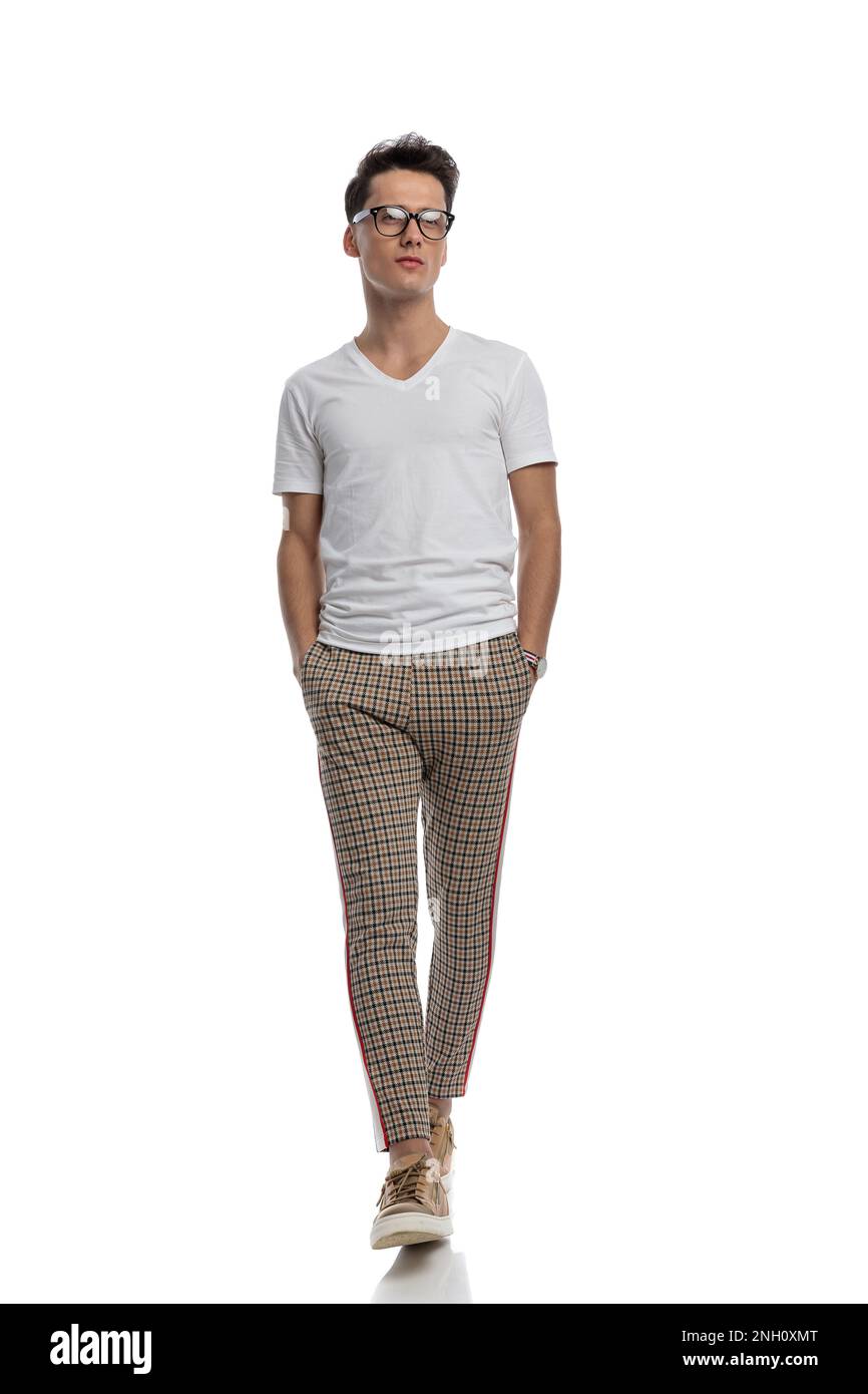casual young man in white tshirt with plaid pants walking with hands