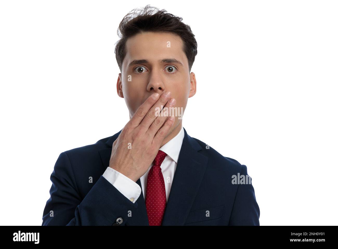 young businessman slapping his mouth and feeling shocked, wearing a suit and tie against white background Stock Photo