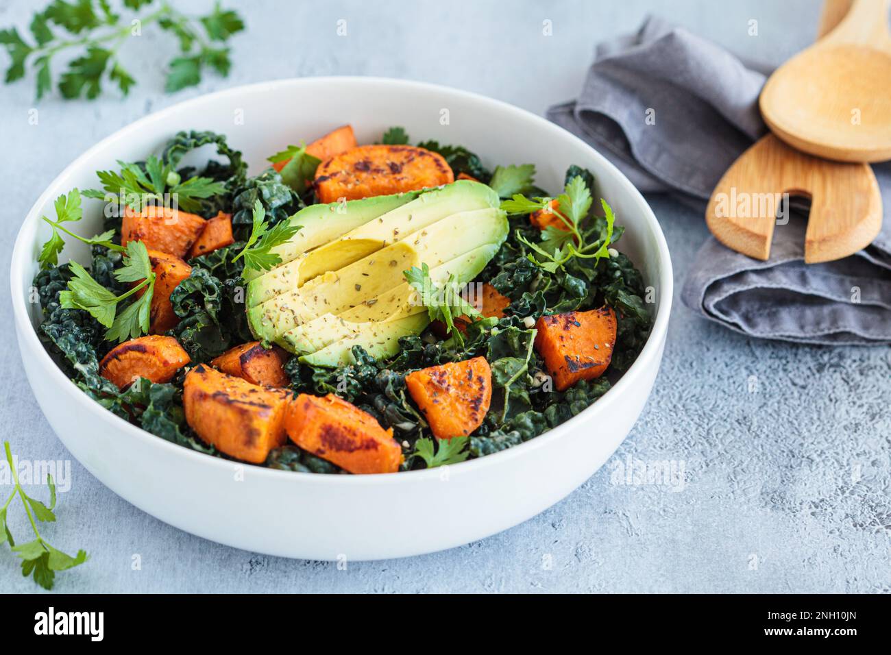 Roasted sweet potato, avocado, kale salad in white bowl. Alternative, healthy, based-plant recipe. Stock Photo