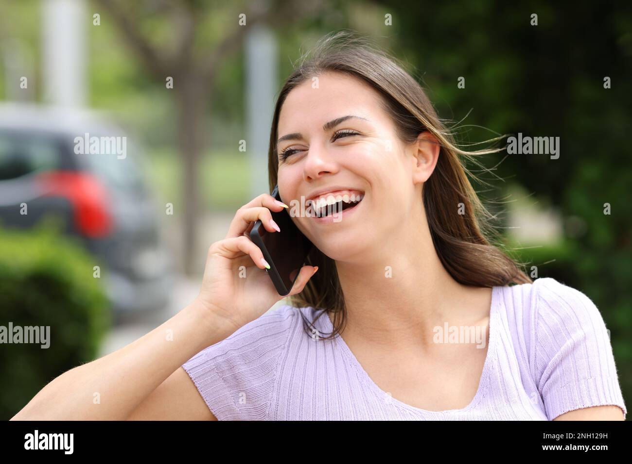 Teen laughing during a phone call in a park Stock Photo