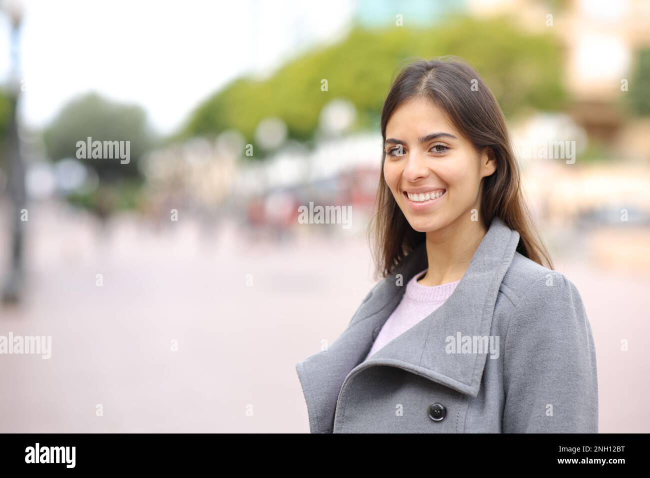 Happy woman looks at camera standing in the street in winter Stock Photo