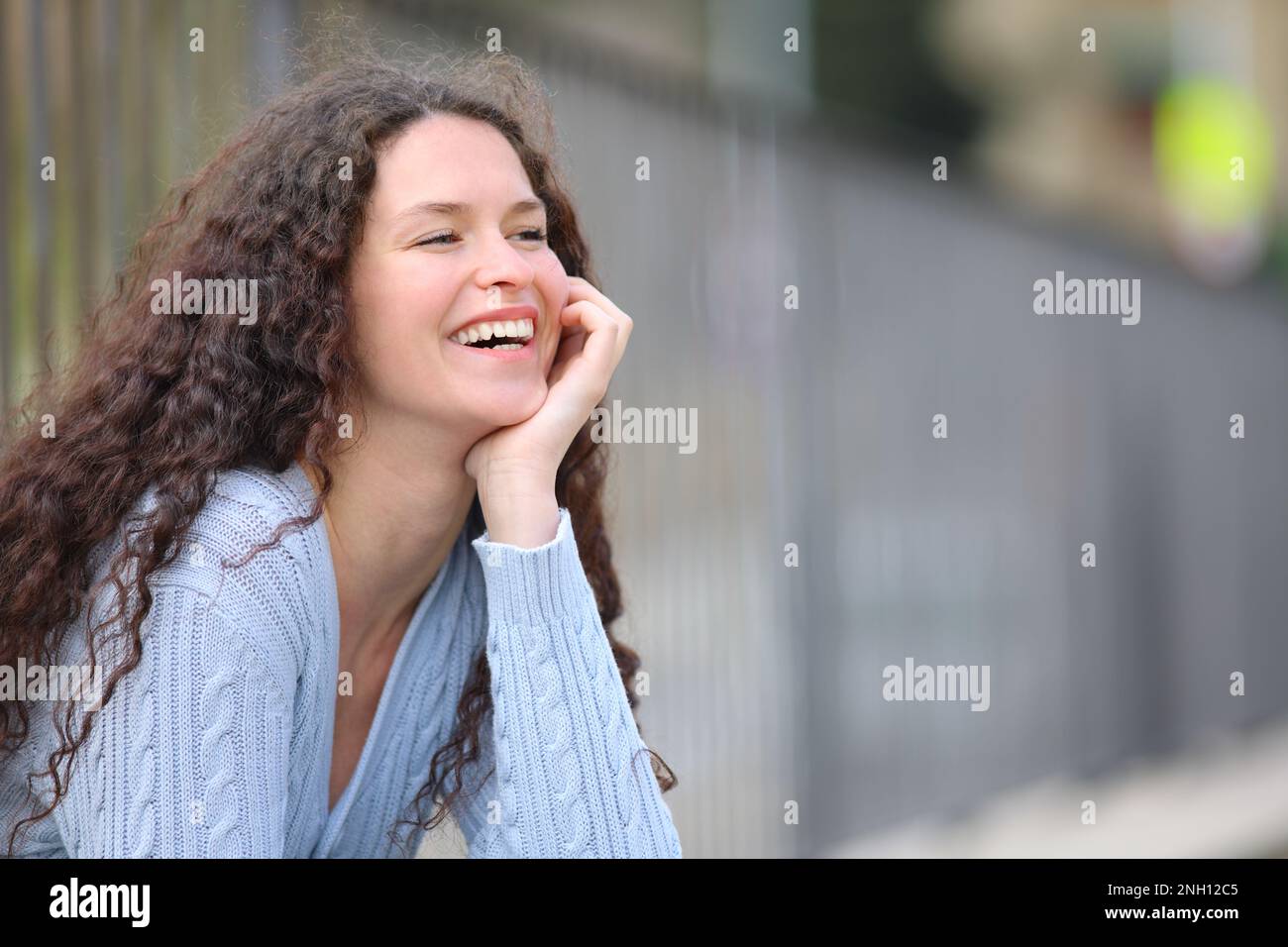 Happy woman laughing sitting in the street Stock Photo