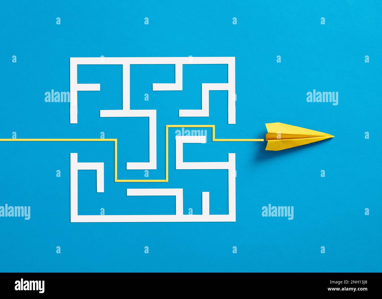 Overcoming the barriers. Conquering the obstacles. Way to success and business solutions. Exit strategy. Paper plane breaking through the maze on blue Stock Photo