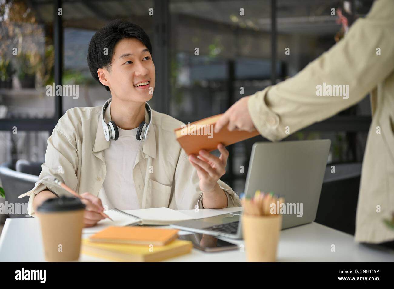 Smart and happy young Asian male college student is talking and doing a ...
