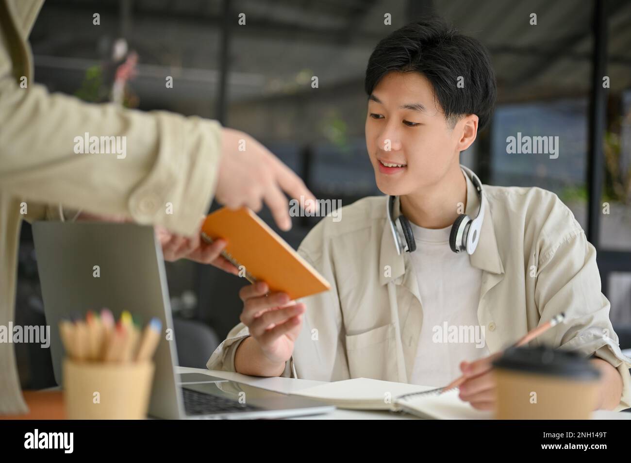 Smart and happy young Asian male college student is doing a school ...