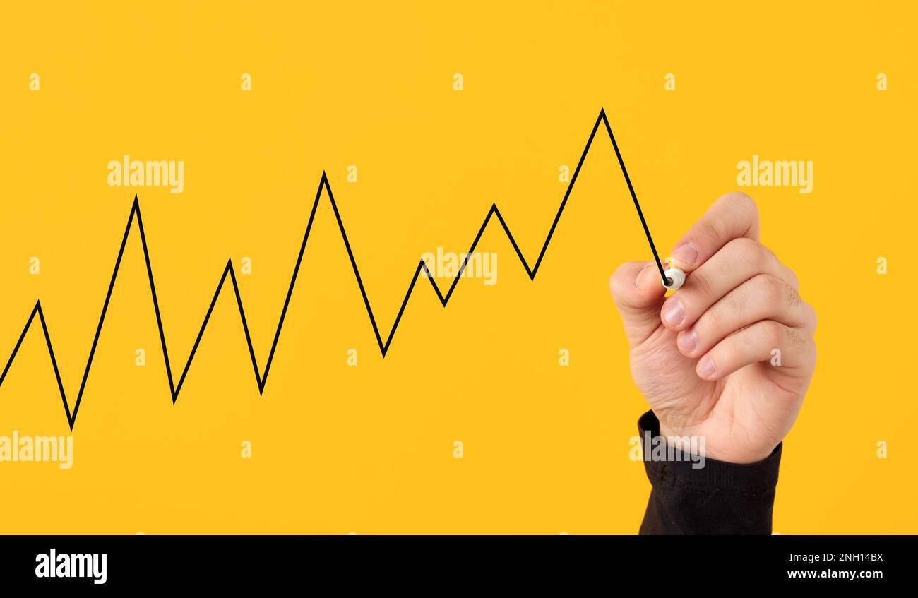 Male hand draws a fluctuating line graph on yellow background. Business ...