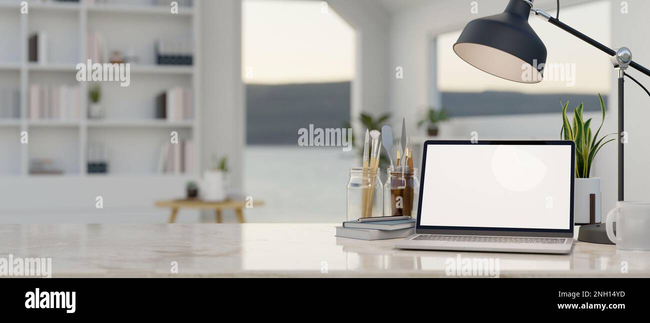 Modern creative workspace with laptop mockup, painting tools, table lamp, decor and copy space on white marble tabletop over blurred background of whi Stock Photo