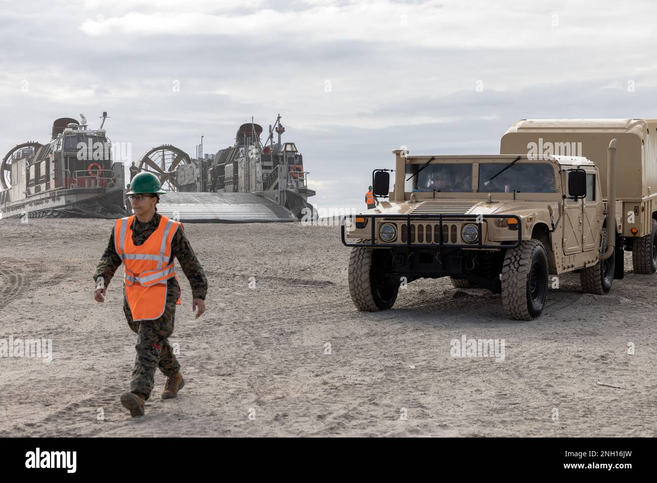 A U.S. Marine with 2d Light Armored Reconnaissance Battalion, 2d Marine Division, ground guides a high mobility multipurpose wheeled vehicle from a landing craft air cushion (LCAC) on Camp Lejeune, North Carolina, Dec. 6, 2022. The main purpose of an LCAC is to transport weapons systems, equipment, cargo and personnel of the assault elements of the Marine Air-Ground Task Force from ship-to-shore and across the beach. Stock Photo