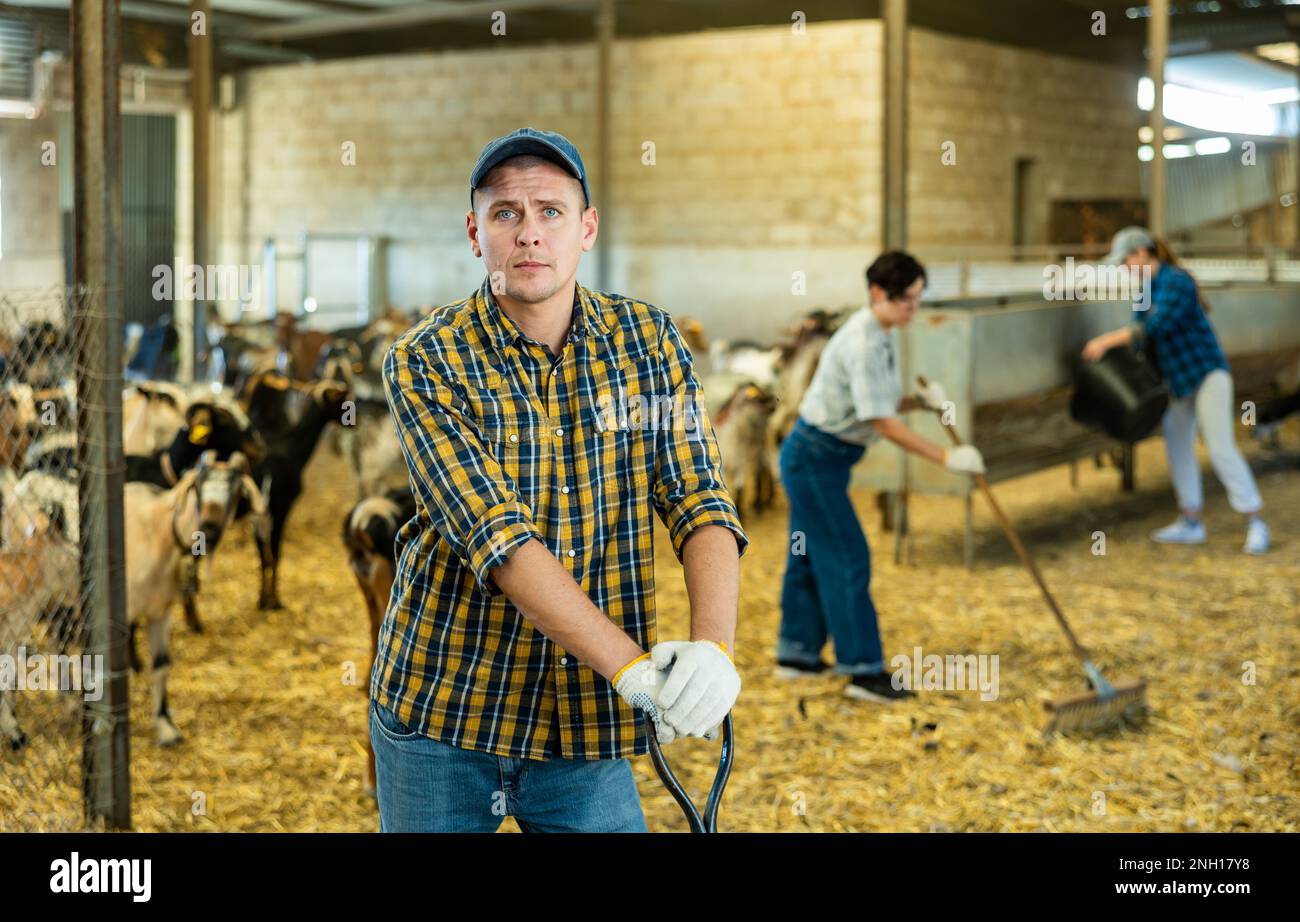 Male farmer holding agricultural tool in goat shed Stock Photo - Alamy