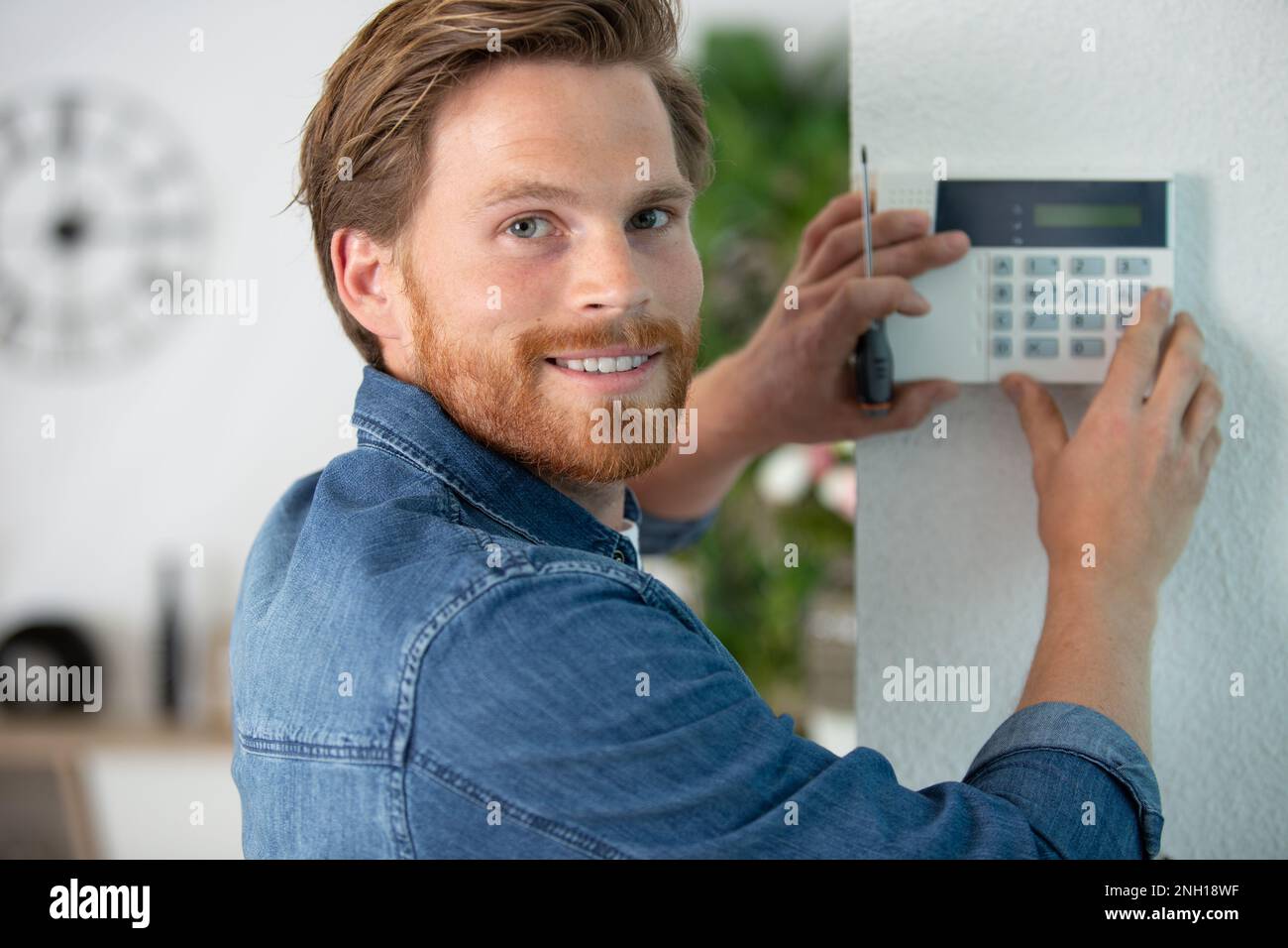 security consultant fitting burglar alarm in room Stock Photo - Alamy