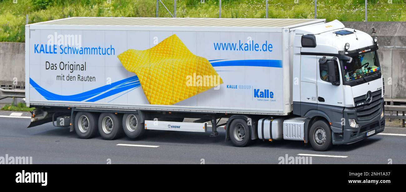 Mercedes Actros tractor unit side front view KRONE rigid articulated trailer for Kalle Group yellow sponge cloth product advert driving on UK motorway Stock Photo