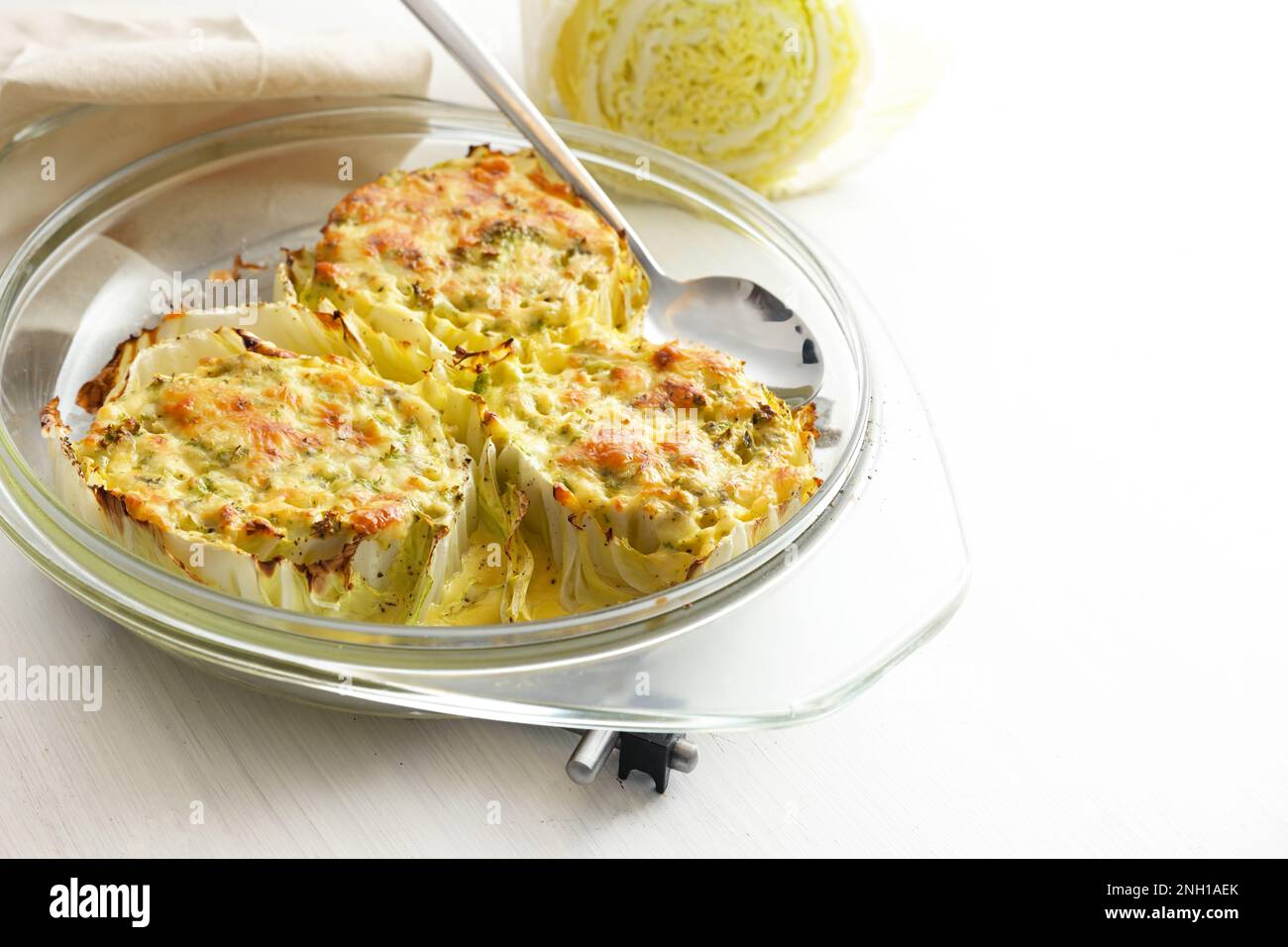 Chinese or napa cabbage gratinated in a glass casserole on a light gray table, healthy cooking, homemade vegetarian meal, copy space, selected focus, Stock Photo