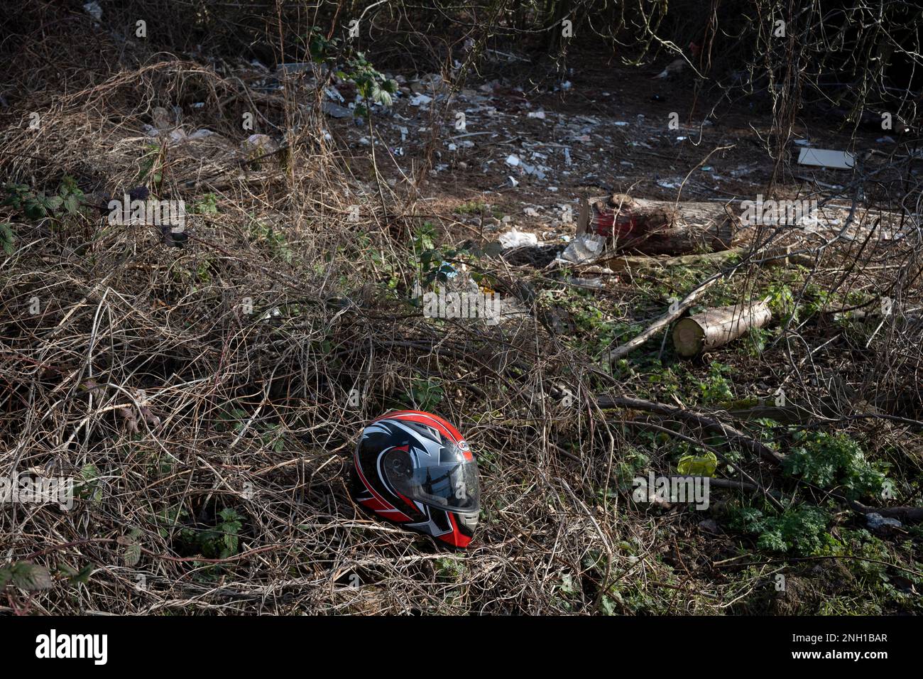 A dumped motorcycle helmet and other fly-tipping along the Darent Valley Path in the Dartford Marshes in north Kent, on 19th February 2023, in London, England. Stock Photo