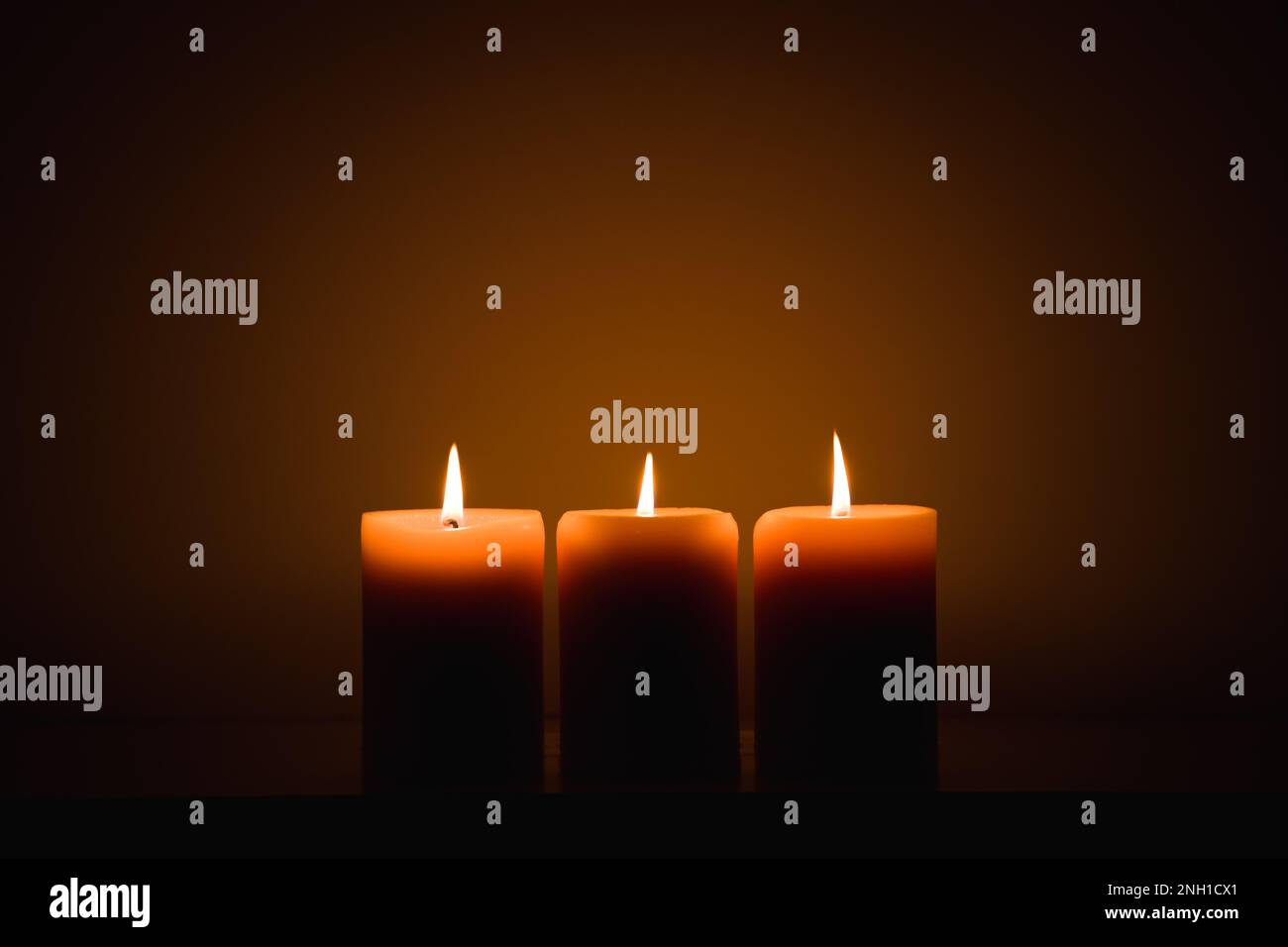 three burning candles in the dark. Memories and blessings Stock Photo
