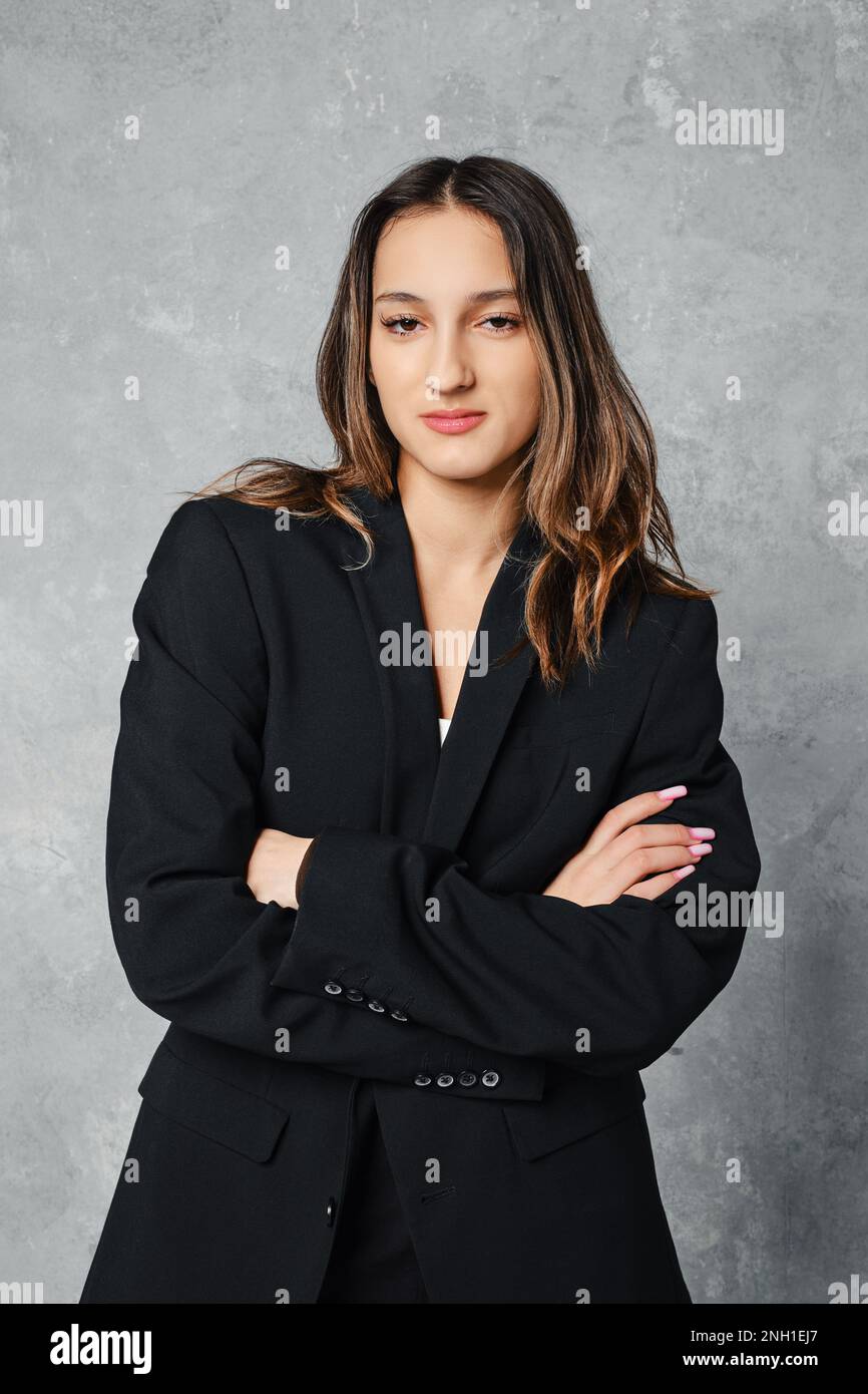 Medium closeup portrait of cute young woman in black blazer with crossed arms Stock Photo