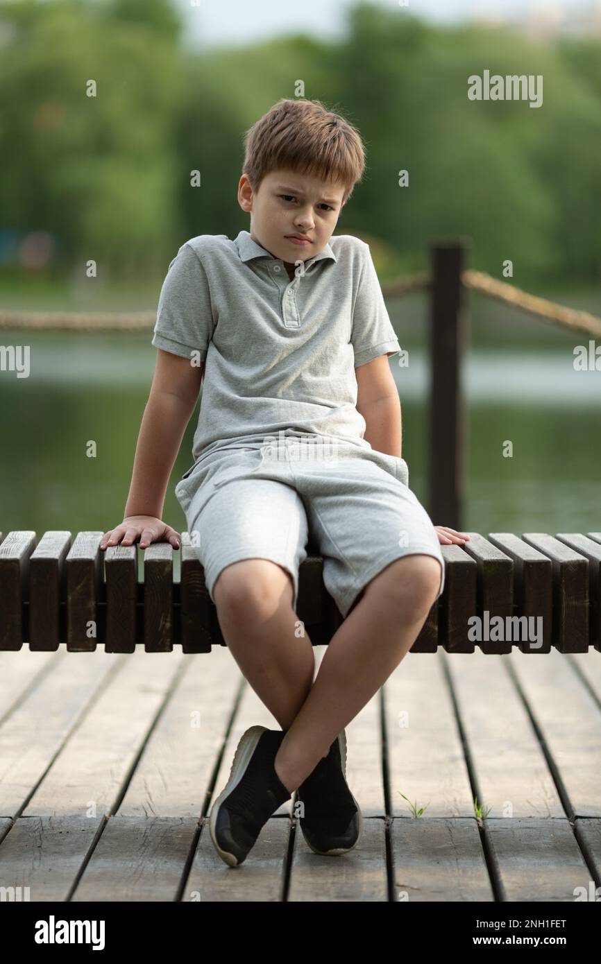 Sad angry boy sitting on a bench Stock Photo