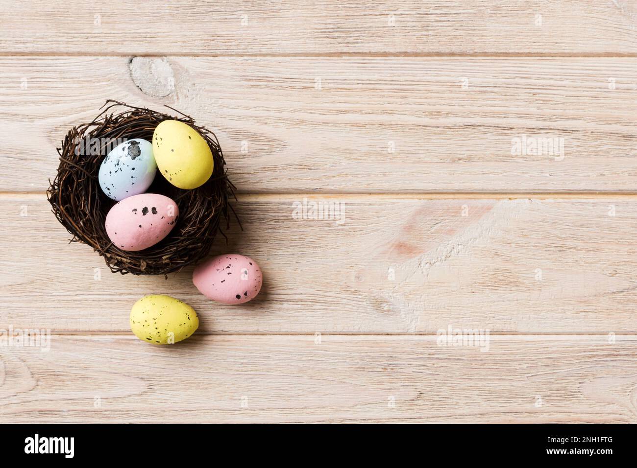 Colorful easter eggs in nest on table background with copy space top ...