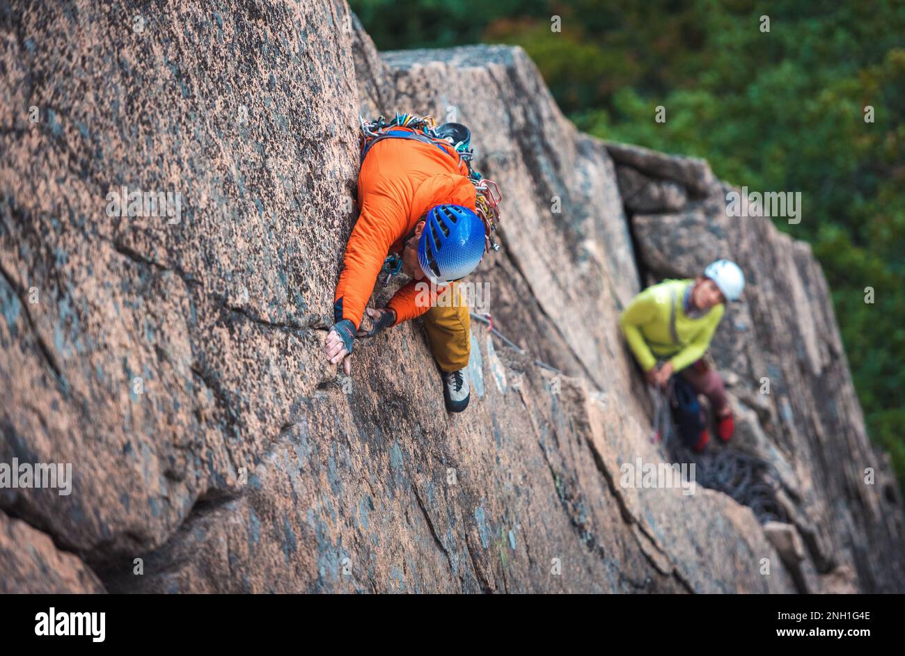 Man rock climbing on rock face with belayer below Stock Photo Alamy