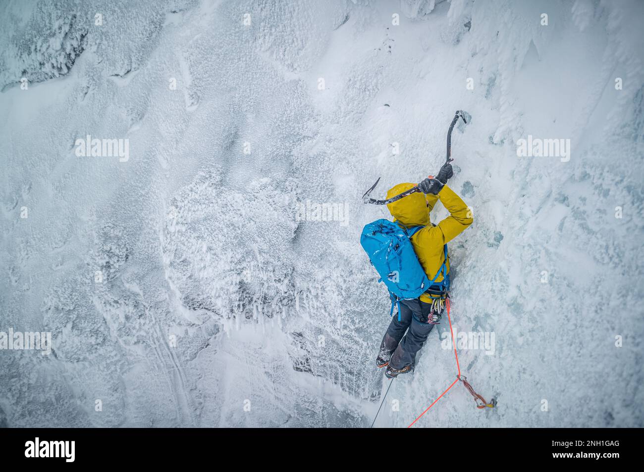 Male mountaineer climbing technical ice wall in cold temperatures Stock