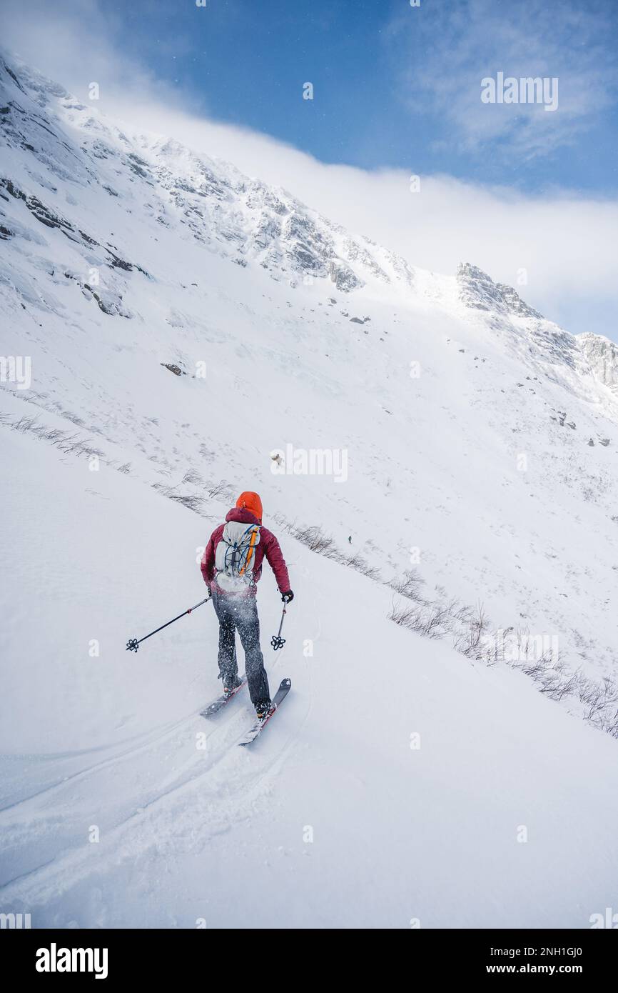 Backcountry skier skiing across open bowl with blue skies Stock Photo