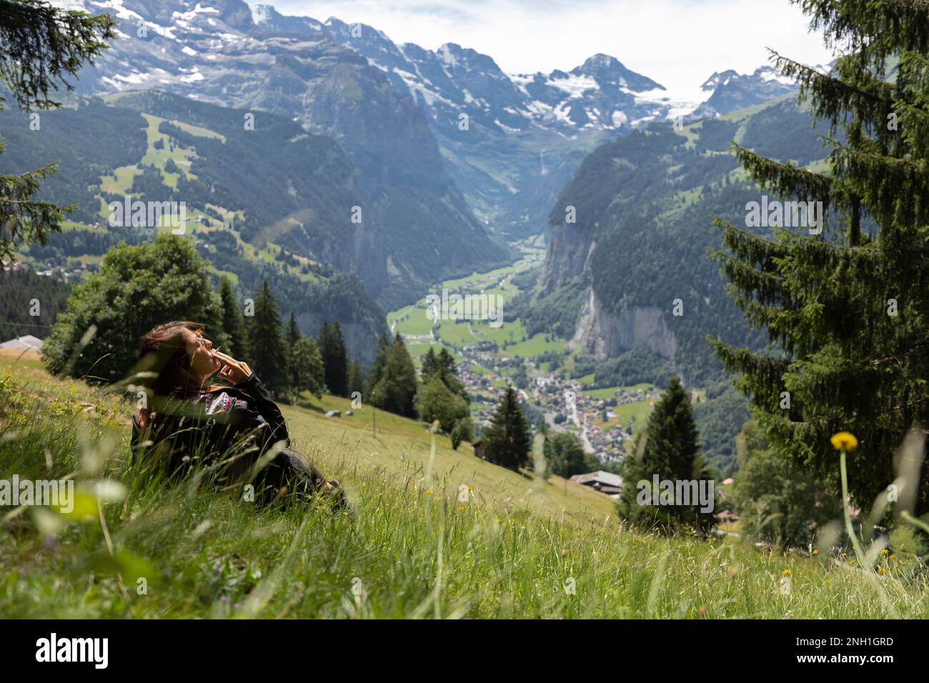 Woman Smoking While Sitting On A Green Meadow, Switzerland Stock Photo