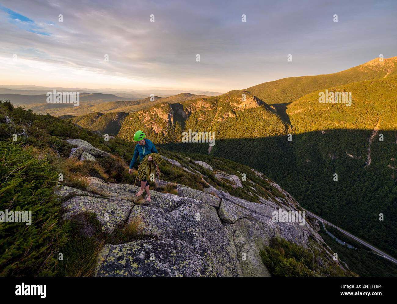Woman carrying climbing rope at the top of a rock climb Stock Photo