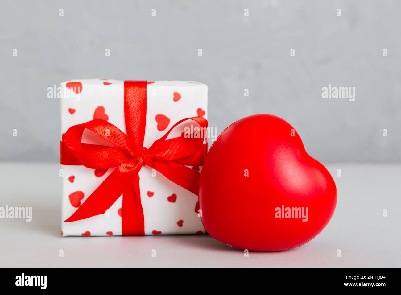 gift box with red bow and red heart on colored background. Perspective ...