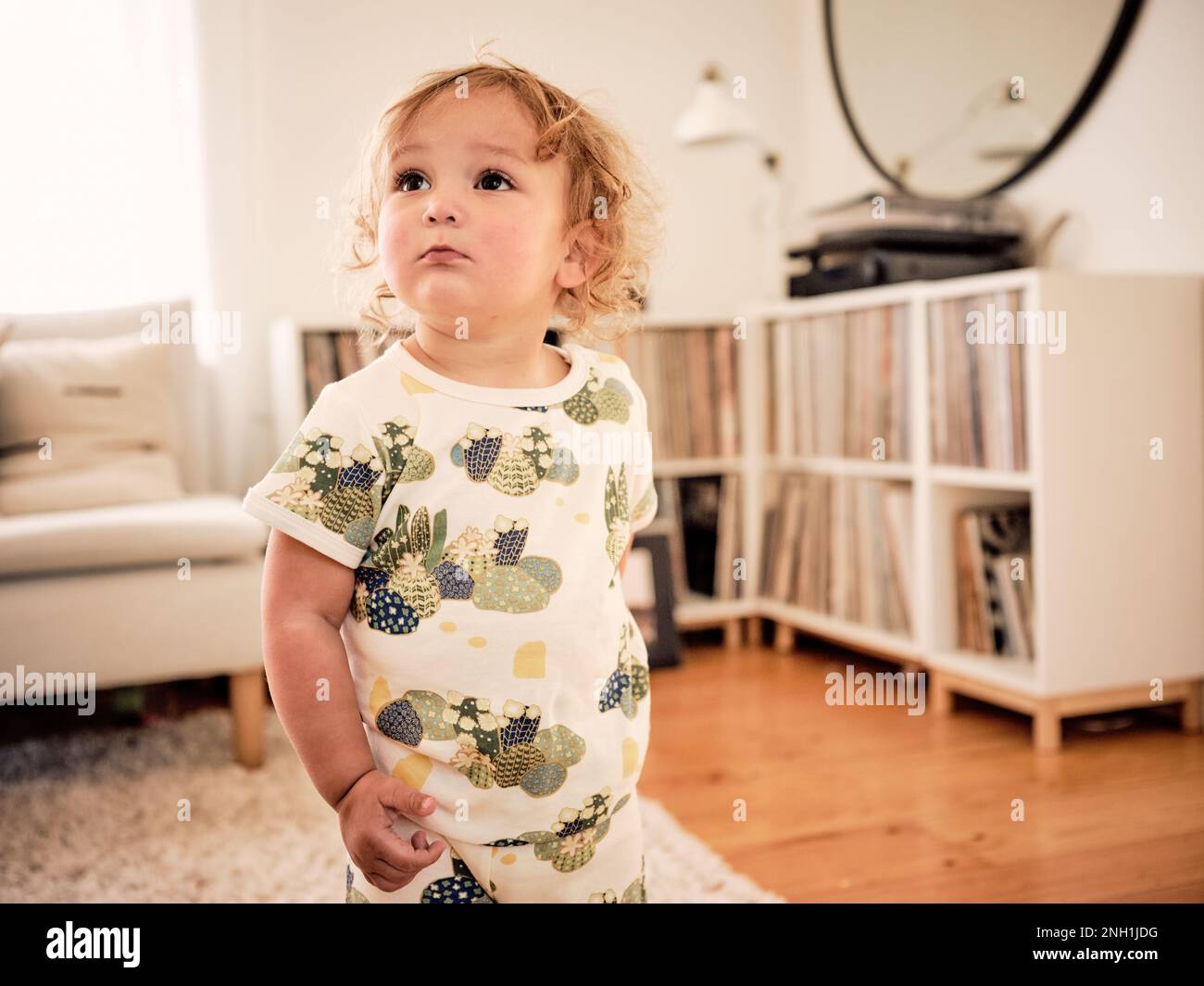 Toddler standing and looking away in family living room Stock Photo