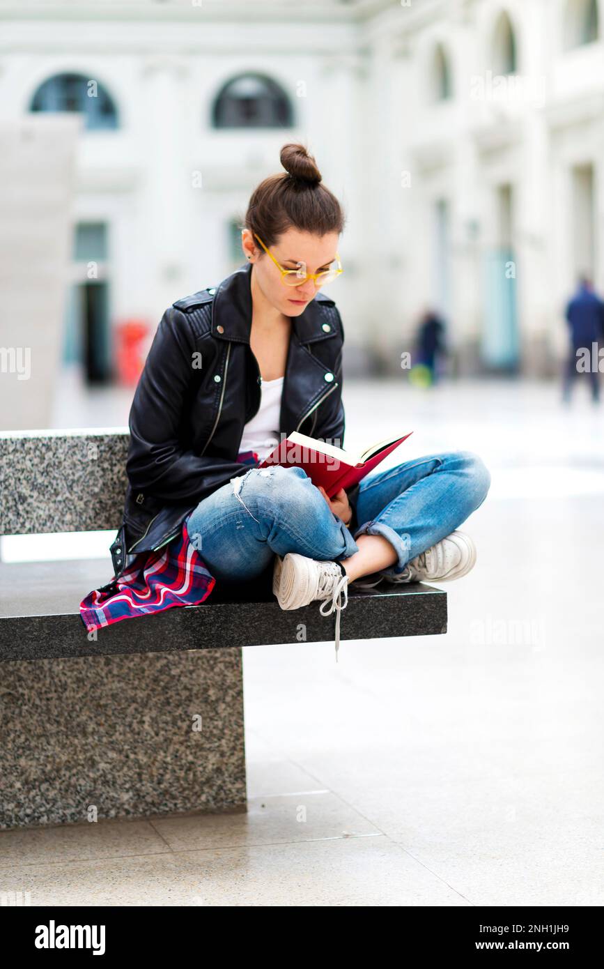 Young woman reading book, waiting at train station Stock Photo Alamy