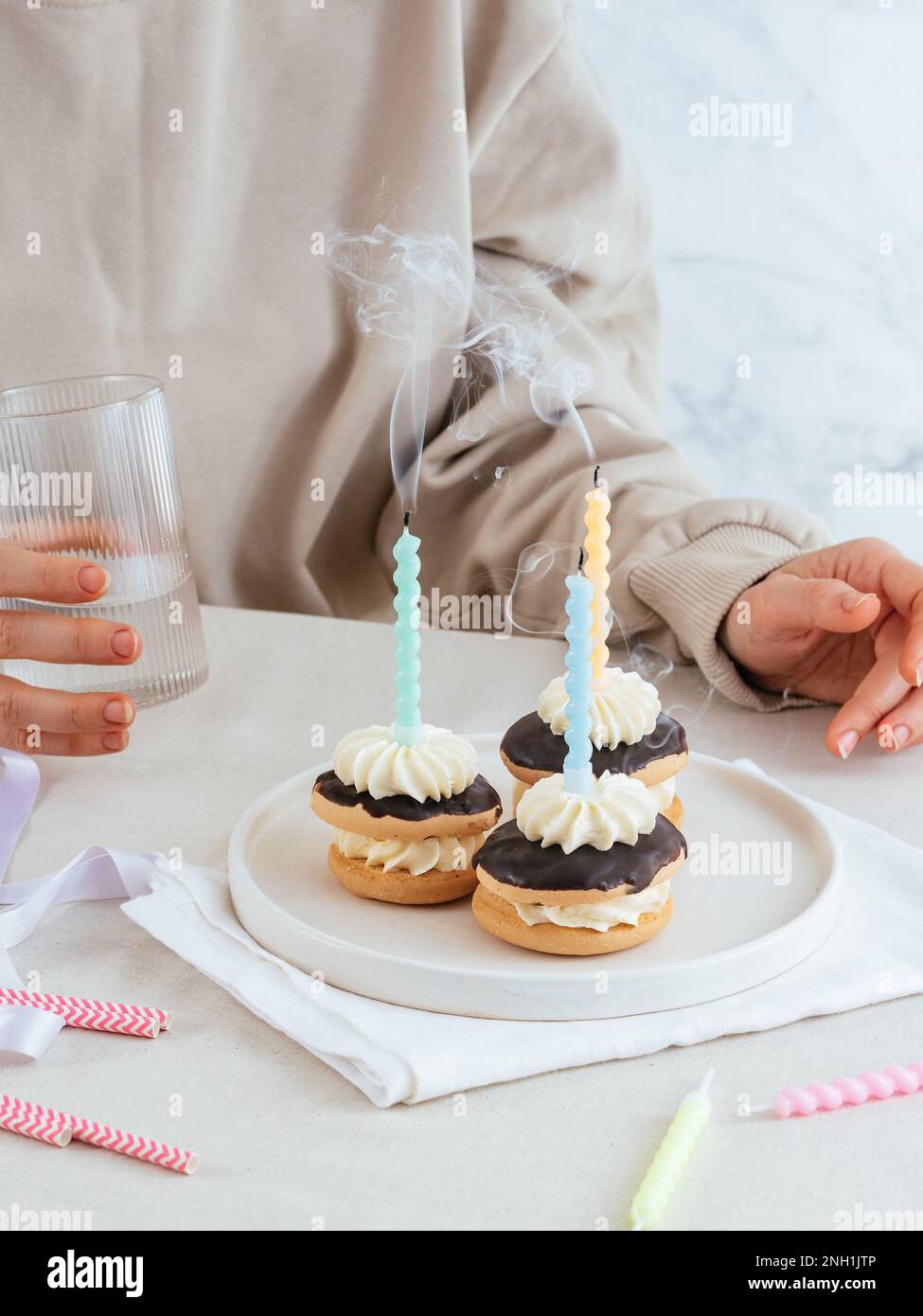 born with candles, a girl holds a glass with a drink in the back Stock Photo