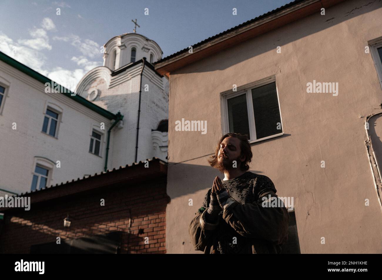 a homeless man prays against the background of a church Stock Photo