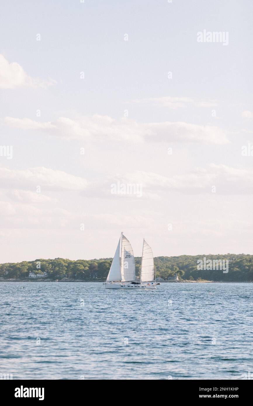 sunny cloud-dotted sky over ocean with boat under full sail Stock Photo