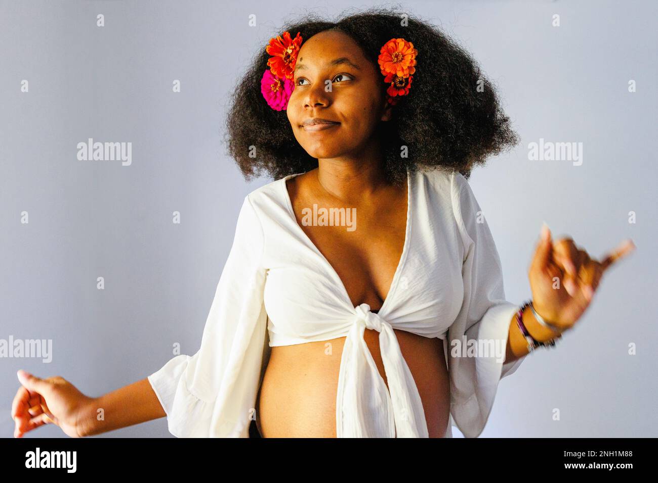 Top-half of pregnant woman dancing with flowers in hair Stock Photo