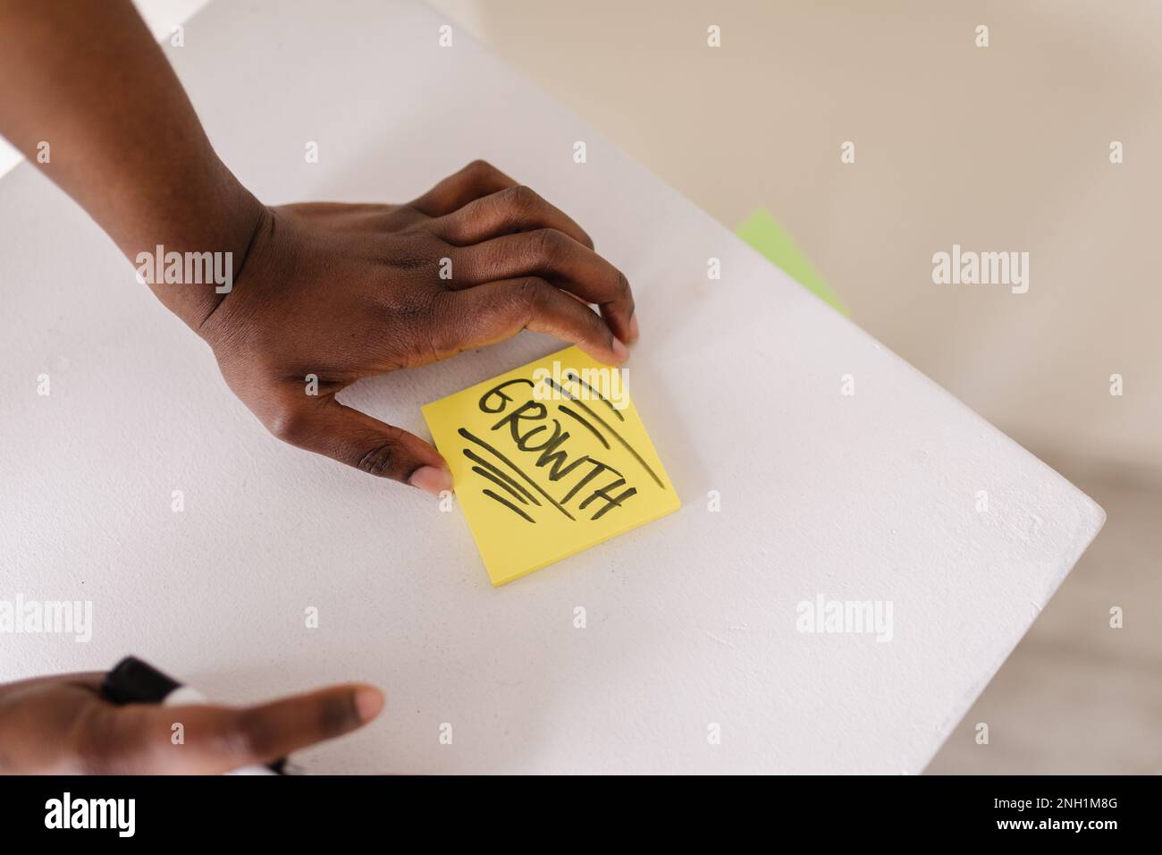 Black person writing growth on a sticky note on white work desk Stock Photo