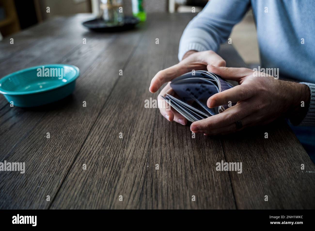 Caucasian Man Shuffling a Deck of Playing Cards at Dining Table Stock Photo