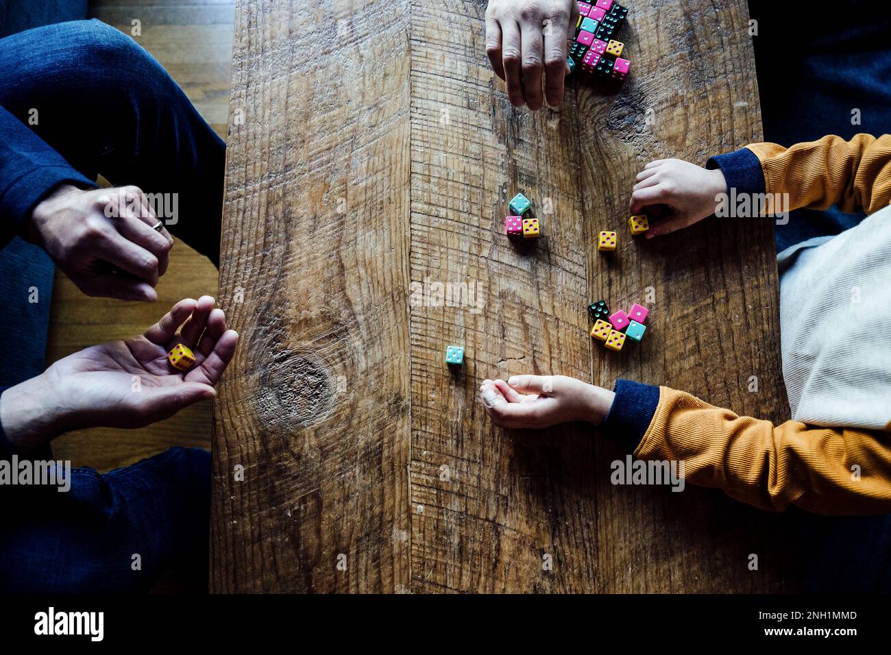 Caucasian Family Playing Colorful Dice Game at Wooden Coffee Table Stock Photo