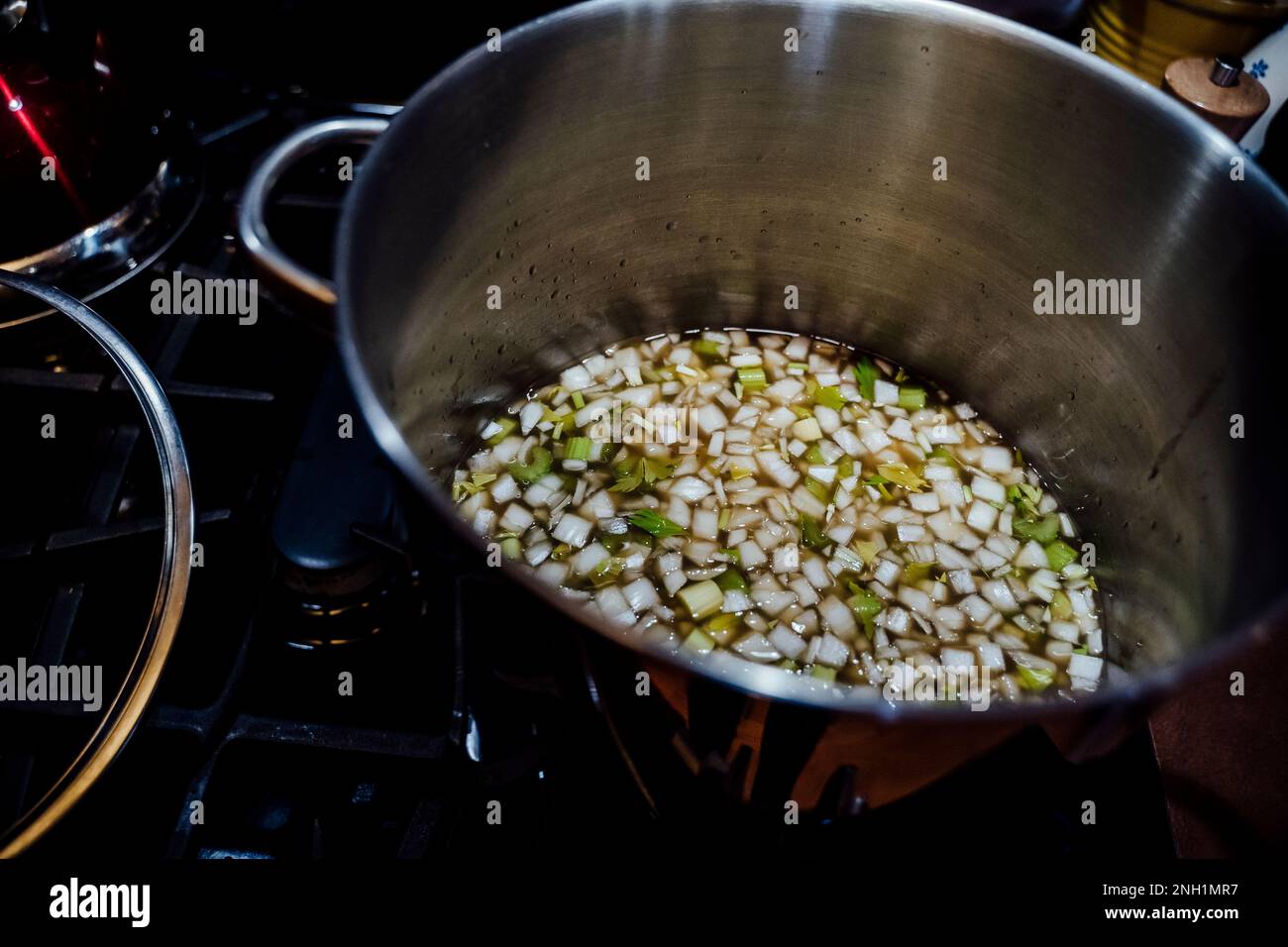 View from Above of Large Soup Pot Warming Onions, Celery and Broth Stock Photo