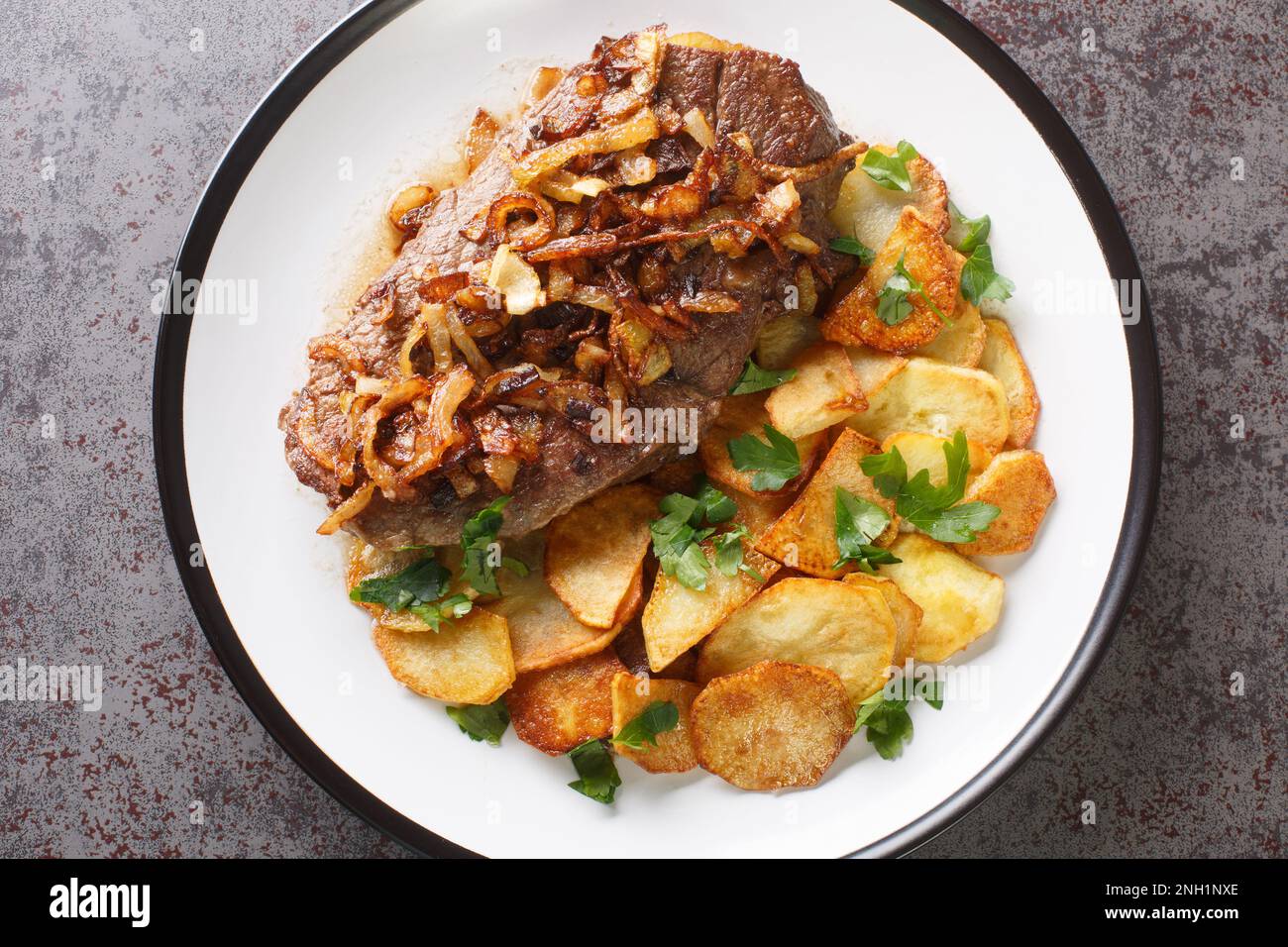 Original and Authentic German Zwiebelrostbraten with onion gravy and fried potatoes Bratkartoffeln closeup on the plate on the table. Horizontal top v Stock Photo