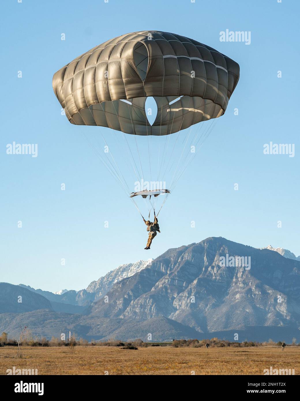 An Italian Army paratrooper with the Brigata Paracadutisti 'Folgore'  prepares to land while conducting an airborne operation alongside U.S. Army paratroopers assigned to the 173rd Airborne Brigade at Frida Drop Zone in Pordenone, Italy, Dec. 7, 2022.     The 173rd Airborne Brigade is the U.S. Army's Contingency Response Force in Europe, providing rapidly deployable forces to the United States European, African, and Central Command areas of responsibility. Forward deployed across Italy and Germany, the brigade routinely trains alongside NATO allies and partners to build partnerships and streng Stock Photo